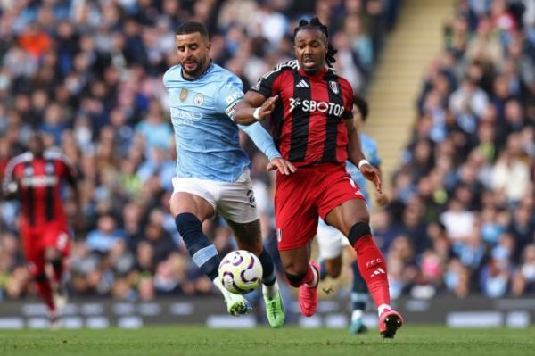 Manchester City's Kyle Walker, left, and Fulham's Adama Traore vie for the ball during the English Premier League soccer match between Manchester City and Fulham at Etihad Stadium in Manchester, England