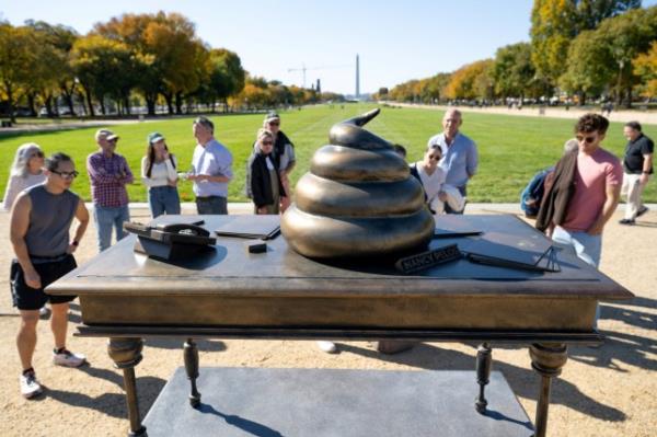 People look at a bro<em></em>nze art installation depicting a pile of feces on former House Speaker Nancy Pelosi's desk