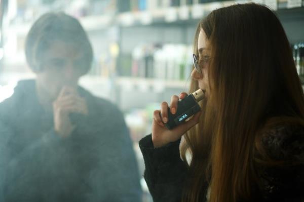 Vape teenagers. Young cute girl in sunglasses and young handsome guy smoke an electro<em></em>nic cigarettes in the vape bar. Bad habit that is harmful to health. Vaping activity.