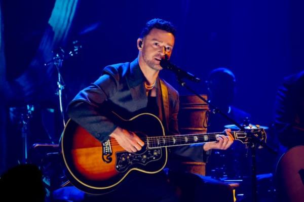 Justin Timberlake singing into microphone with guitar