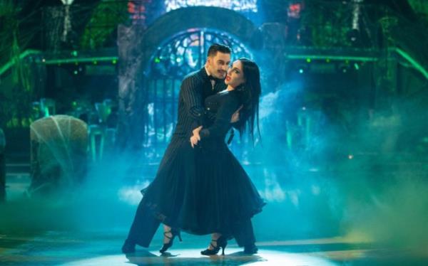 Giovanni Pernice and Michelle Visage dressed as the Adams Family on Strictly Come Dancing. She is leaning back as Giovanni holds o<em></em>nto her.