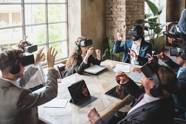 Group of people in suits wearing virtual reality headsets sit around a co<em></em>nference table