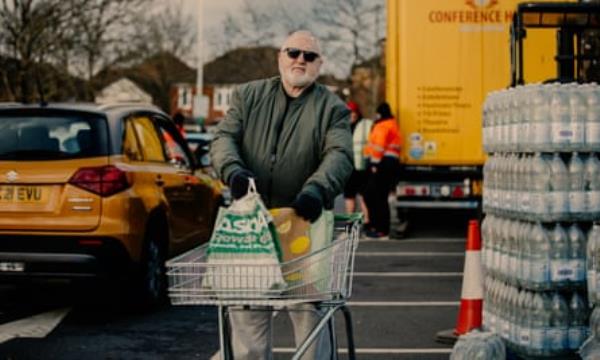 Roger Brown standing in a car park with a trolley and shopping bags