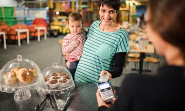 A woman makes a payment in the cafe of a soft play centre