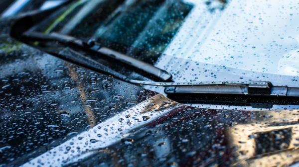 Black car with water dro<em></em>plets all over the hood and windshield