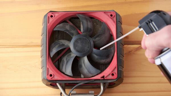 Spraying compressed air into a dusty computer fan.