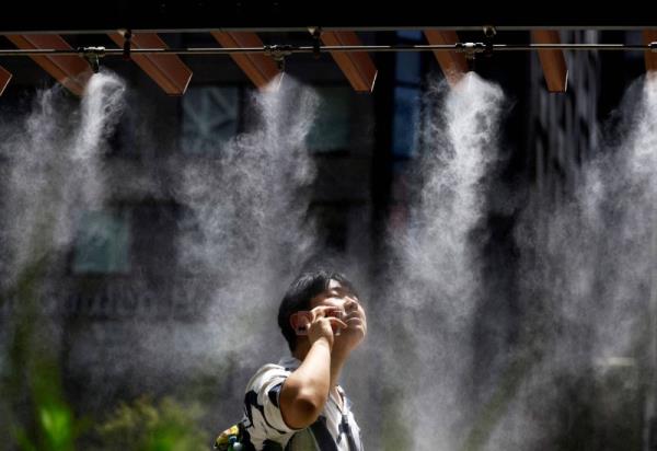 A man takes a break under a cooling mist on July 9. The summer of 2024 tied with the summer of 2023 as being the hottest on record. 