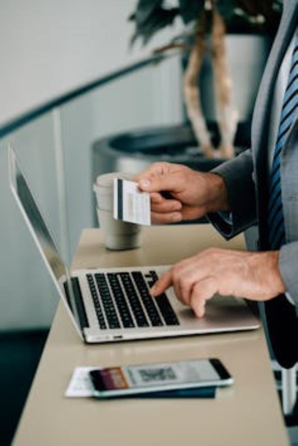 Close Up Photo of Man's Hands Using Laptop Computer and Credit Card