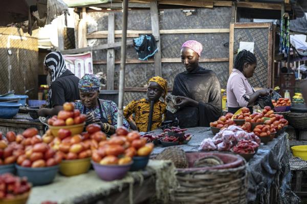 A woman counts mo<em></em>ney as other women engage in other activities