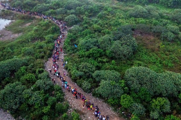 Aerial view of large number of migrants crossing a cleared out jungle path.