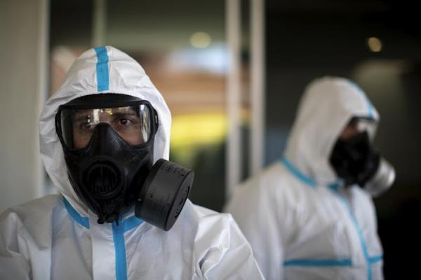 Two workers wearing respirators, eye protection and protective suits.