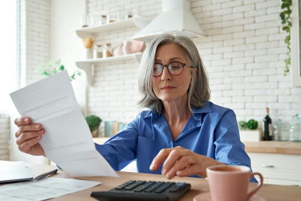 Woman wearing glasses reading a new<em></em>line while seated at a table