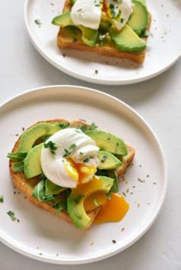 Poached eggs on toasted bread with avocado and herbs.